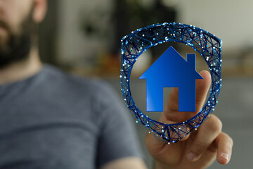 Man's hand touches a digital home icon, representing house protection, insurance, or smart home...