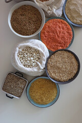 Bowls and bags full of various healthy grains and legumes. Top view.