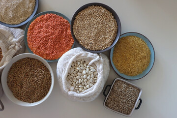 Bowls and bags full of various healthy grains and legumes. Top view.