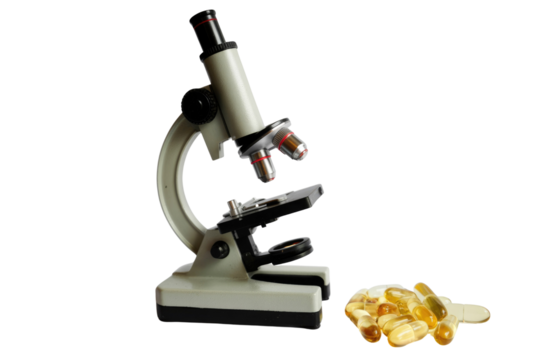 A scientific microscope stands beside a pile of golden gel capsules, suggesting research in pharmaceuticals, nutrition, or health sciences. background removed