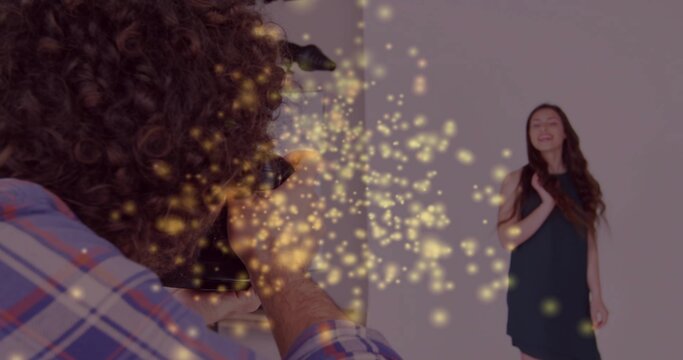Man holding DSLR camera photographing model in black dress against backdrop with bokeh, copy space - Powered by Adobe
