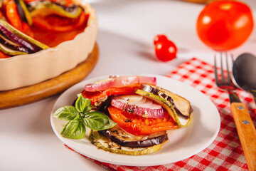 Homemade ratatouille with slices of zucchini, eggplant, tomato, red onion and herbs brushed with olive oil. Vegetarian meal.
