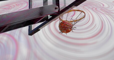 Capturing orange basketball passing through hoop rim and net with black metal arm, spiral backdrop