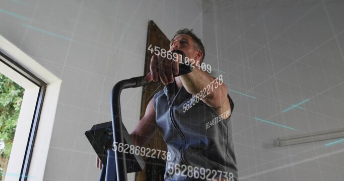 Exercising adult man on elliptical in home gym, wearing earbuds, tracker wristband tracking metrics - Powered by Adobe