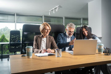 Multiethnic team discussing business strategy around laptop creative office environment...