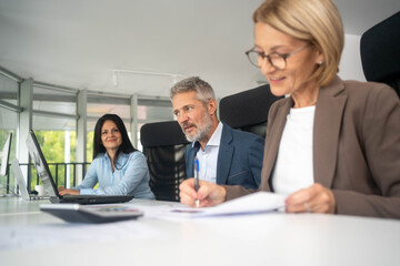 Multiethnic team discussing business strategy around laptop creative office environment collaboration	
