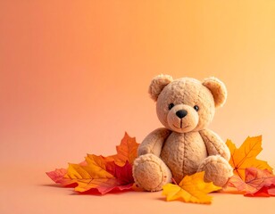 オレンジ色の背景にふんわり座るぬいぐるみのテディベア。周囲にはカラフルな紅葉の葉が散り、秋のあたたかさと優しさを感じる可愛いイメージ構成。