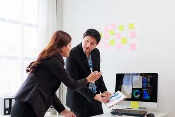 Businesspeople analyzing performance charts and graphs on a computer screen and clipboard in a modern office, planning strategy