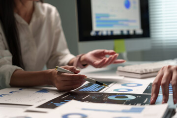 Business partners analyzing financial data, discussing market reports and strategy, pointing at charts during a meeting