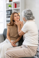 Senior woman gently touching young woman's face, expressing care and intergenerational affection while bonding at home