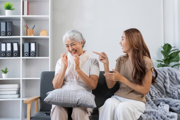Smiling Asian woman and elderly grandmother enjoying fun time together, bonding and sharing genuine happy moments