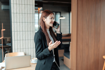Young Asian businesswoman using mobile phone for a professional call, expressing confidence and...