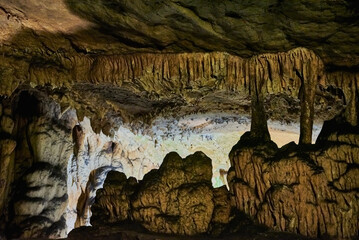 Vadu Crisului Cave in Bihor, Romania, features impressive limestone formations. Stalactites hang from the ceiling, while stalagmites rise from the floor, some meeting to form columns