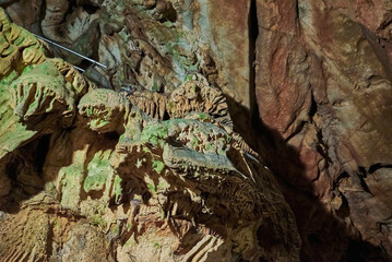 Vadu Crisului Cave in Bihor, Romania, features impressive limestone formations. Stalactites hang from the ceiling, while stalagmites rise from the floor, some meeting to form columns