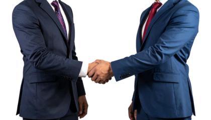 Two men in suits shake hands, close up on their arms and mid-torso, black backdrop