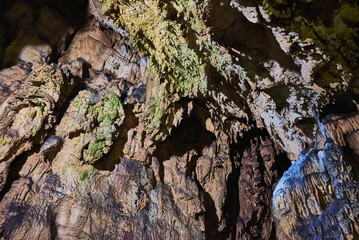 Vadu Crisului Cave in Bihor, Romania, features impressive limestone formations. Stalactites hang from the ceiling, while stalagmites rise from the floor, some meeting to form columns