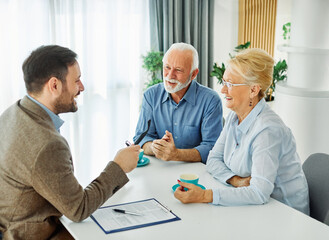 Senior couple having a meeting with an agent, businessman, salesperson or doctor in his office