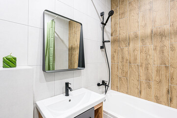 Modern bathroom featuring white and wood-look tiles, black fixtures, and a contemporary sink with a mirror