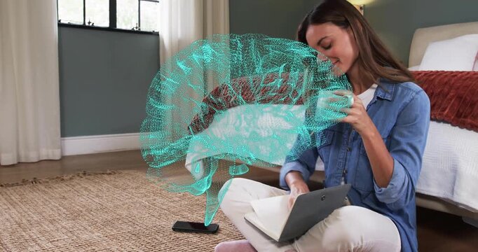 Mid adult woman tapping tablet, rotating brain hologram for study, sipping mug and writing notes