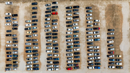 Aerial zenithal view of a car park. There are many cars parked on this unpaved ground.
