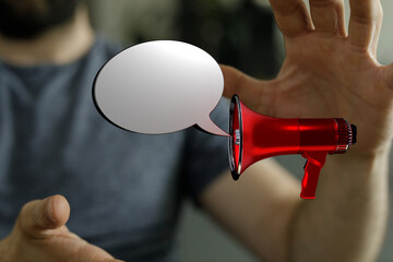 A man's hand with megaphone and speech bubble delivering a message. Marketing, announcement, news,...