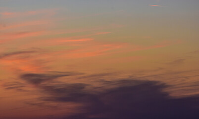 Vibrant sunset colors illuminating fluffy pastel clouds above horizon
