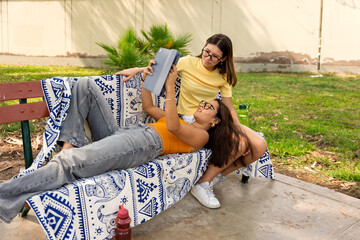 Teenage girls enjoying birthday celebration in park looking at digital tablet