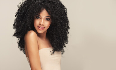 Beauty portrait of african american woman with clean healthy skin on beige background. Smiling...