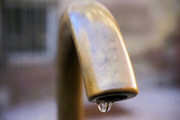 Alter brauner Wasserhahn aus Kupfer mit Wassertropfen über Brunnen auf Platz in Altstadt 
