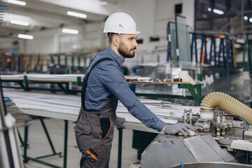 Factory worker operating machinery producing aluminum and pvc windows and doors