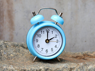 Blue retro alarm clock isolated on a stone. Concept of winter and summer time.