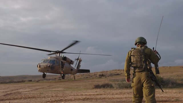 Cinematic slow motion ground view of a military Black Hawk helicopter and special forces soldiers showing teamwork during a medical evacuation operation at sunset