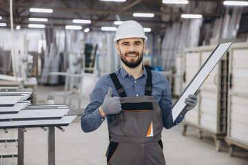 Factory worker holding PVC window frame and making thumbs up gesture