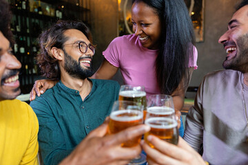 Group of young multiracial happy people drinking beer and talking in a pub, enjoying happy hour. Friendship concept