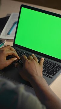 Hardworking male typing on laptop with blank green screen