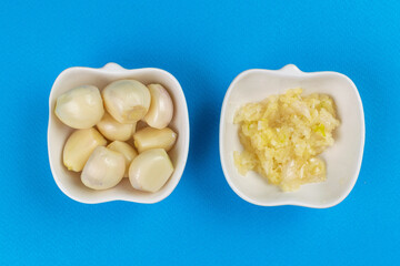 Fresh Garlic Cloves and Minced Garlic in Bowls on Blue Background