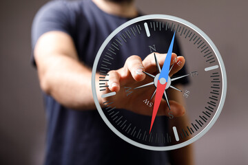 A person's hand pointing towards a compass, representing guidance, direction, travel, decisions,...
