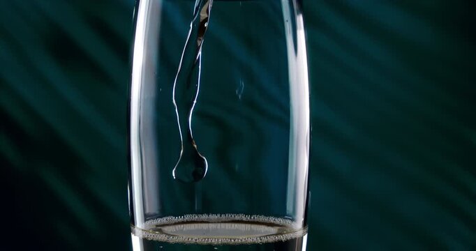 Slow Motion Close Up of Champagne pouring into a glass under blue lights, liquid crystal and bubbles shining in elegant motion, symbol of celebration and timeless refinement at 1000 fps