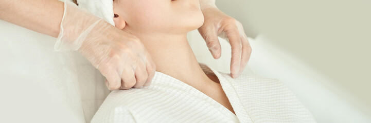 Relaxing spa massage on caucasian female adult wearing white robe and towel with therapists hands.