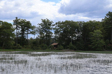 A small lakefront cabin sitting at the edge of the forest on a lake in the Adirondacks.