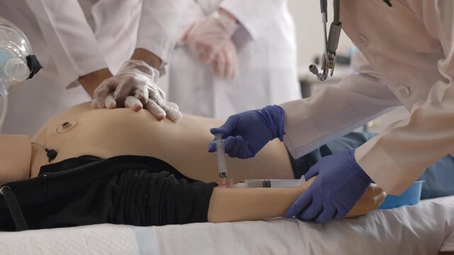 Medical students practicing cpr and iv injection on a dummy