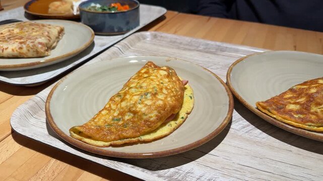 Breakfast omelettes with cheese and ham served on wooden trays in a cozy dining setting