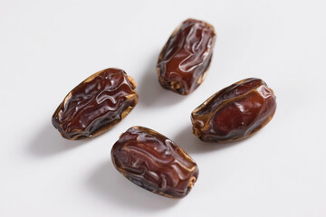 Fresh, natural, brown dates with wrinkled surface scattered on pure white background, highlighting plump texture, glossy sheen, and organic food concept for healthy eating.