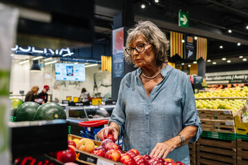 Senior woman choosing fresh fruit in supermarket