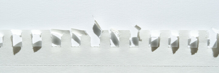 Close-up of torn white paper strips against light background with shadows and textures.