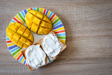 Delightful breakfast spread featuring creamy toast and vibrant mango slices on a colorful striped...