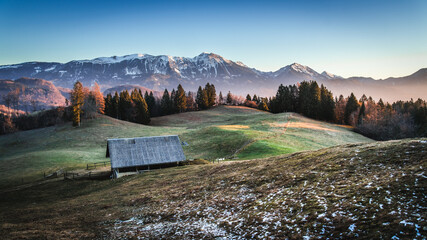 Snow-dusted mountains and a rustic cabin at sunrise.
