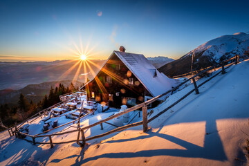A cozy mountain hut bathed in the warm glow of sunrise.
