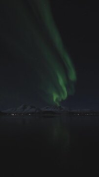 Timelapse view of green aurora with full-moon dancing over Malangen Fjord