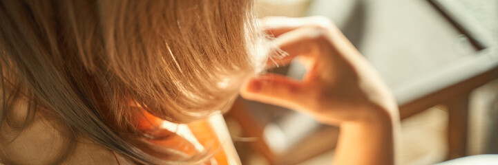 Fototapeta premium Young caucasian female with blonde hair reading indoors in sunlight, close-up.